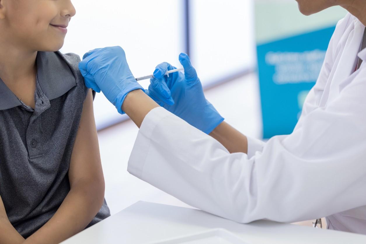 a decorative picture of a young adult getting a vaccine injection by a health care worker